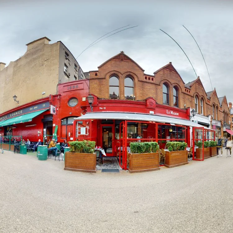 Exterior view of La Maison Restaurant showcasing its charming red facade and inviting outdoor seating, captured during the French Restaurant Virtual Tour.