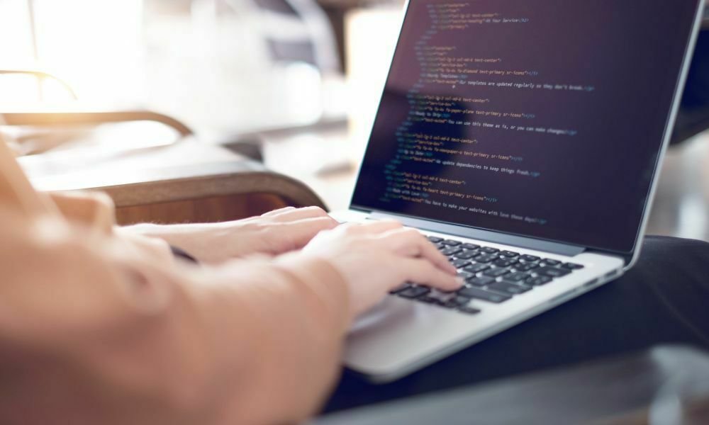 Person typing code on a laptop for custom website design and development, representing digital solutions in Ireland.