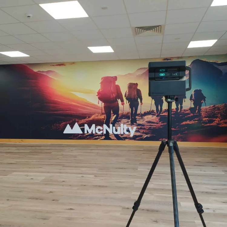 Office wall featuring an inspiring hiking-themed mural and advanced 3D scanning equipment.